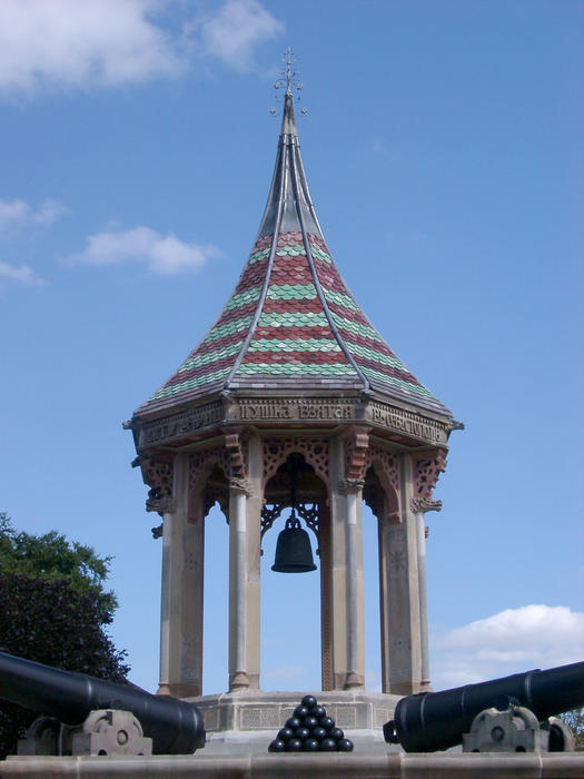 an ornate commemorative bell tower with tiled shingle pattern roof