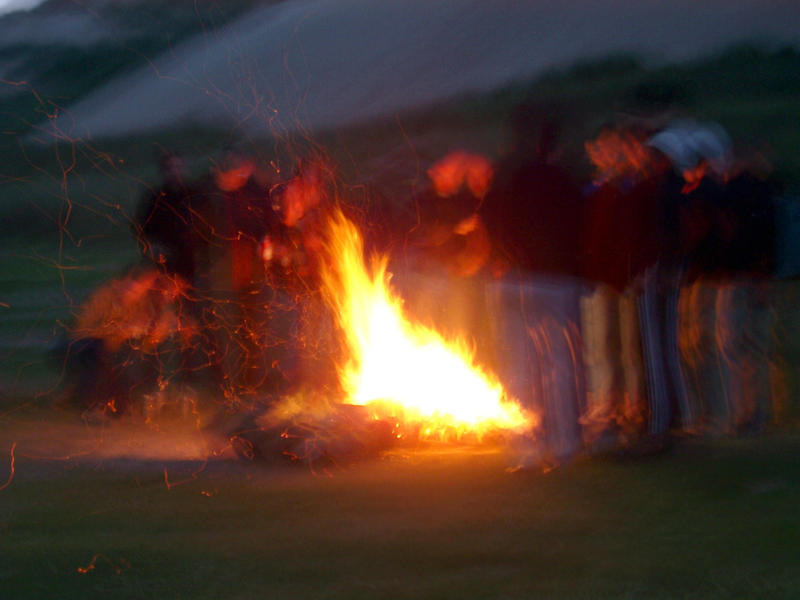 a group of people standing around a camp file at dusk