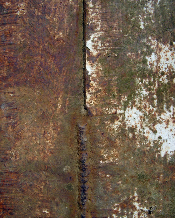 close up on the texture of a rusty metal sheet with a weld line