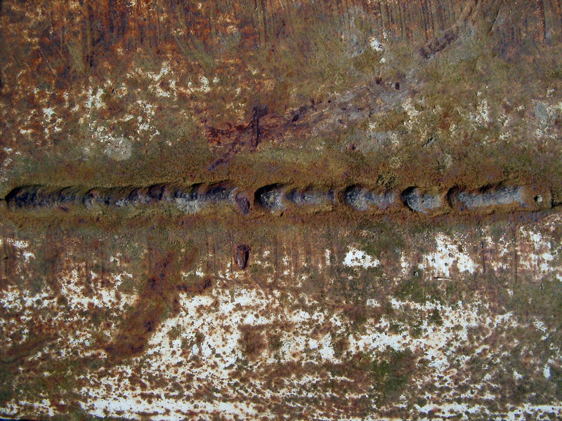 close up on the texture of a rusty metal sheet with a weld line