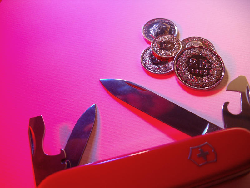 detail of the blades of a red swiss army knife and a selection of swiss coins