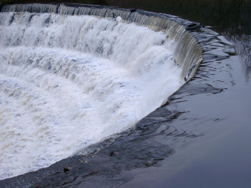 water cascading over a a curved weir