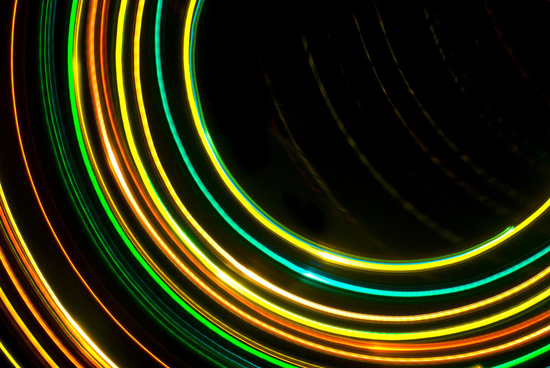 a pattern of green orange and yellow light trails moving around a central out of frame point