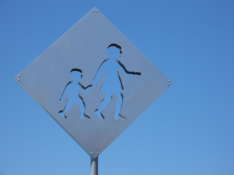 a metal warning sign with pictogram children, symbolic of crossing the road