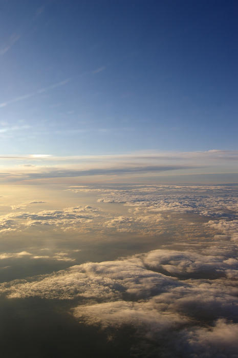 a view of clouds below from a high altitude aircraft as the sun sets