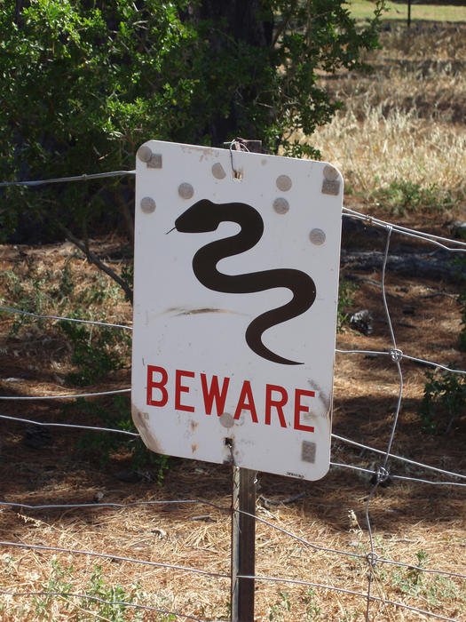 a warning sign with beware and a snake symbol