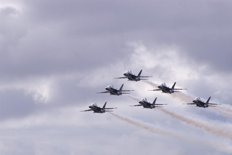 Navy blue hornets performing a fly-by with smoke trails