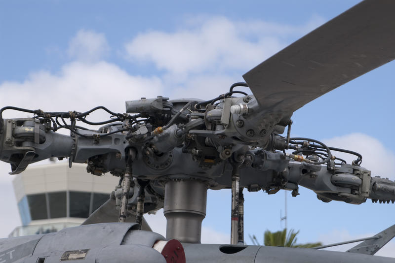 closeup on the rotor of a helicopter with the airport control tower to the rear