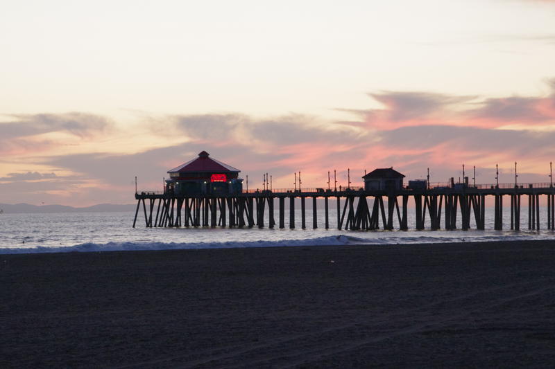 sunset through the pier structure at huntington beach, california