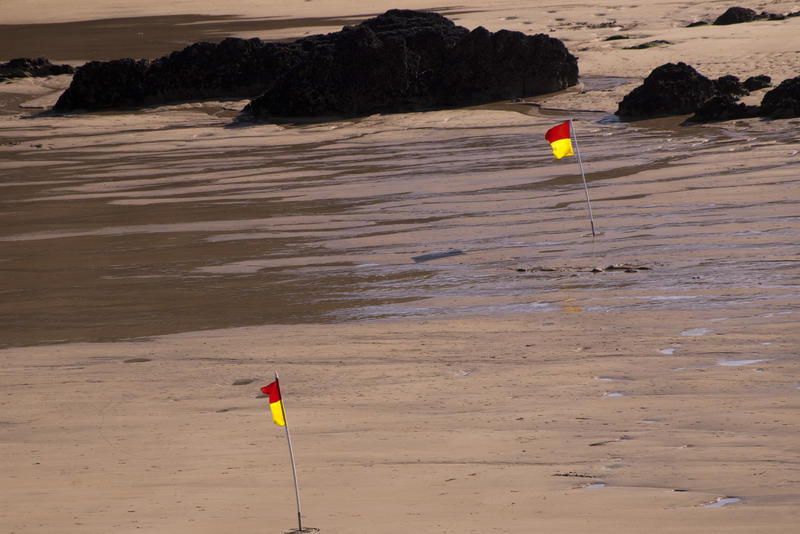 yellow and orange flags on a beach indicating the area patrolled by life guards