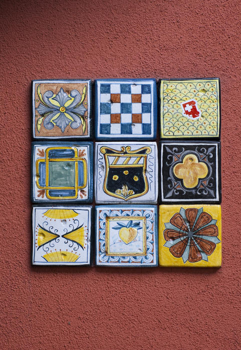 decorative glazed painted tiles on a terracotta coloured wall