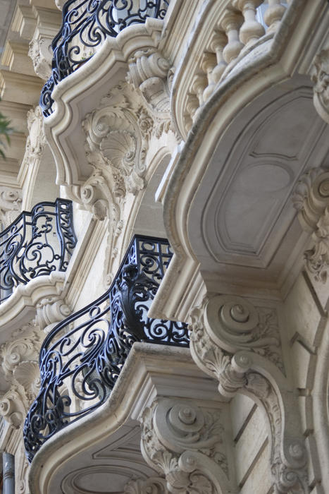 rows of ornate cast iron balconies on the side of a building in a french town