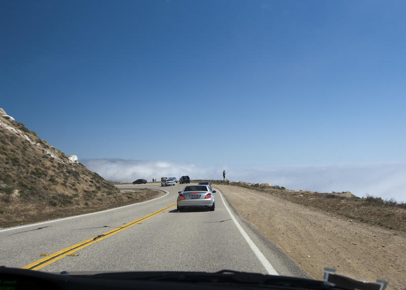 a drive along the scenic highway 1 along california's coast, tourist stopping to enjoy the cliff top view