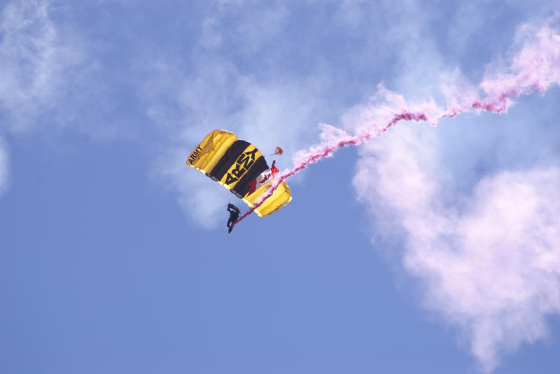 a tail of pink smoke left behind an army paratrooper