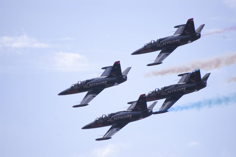 patriots jet team flying an airshow routine with red white and blue smoke trails