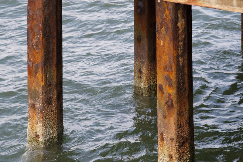 metal pier supports covered in rust and barnacles