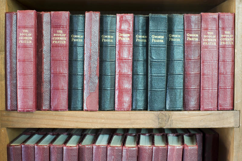 a church bookshelf with rows of well thumbed leather bound prayer books