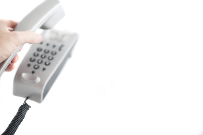 a high key image of a hand picking up a modern style desk phone