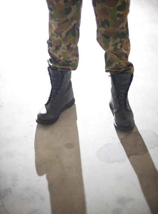 backlit image of someone wearing army combat boots and pants