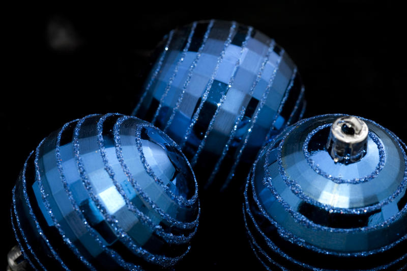 three metallic blue christmas baubles laid on a dark backdrop
