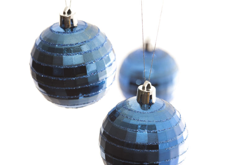 three blue christmas baubles hanging with a white backdrop