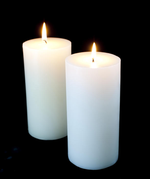 two plain white christmas candles on a black background