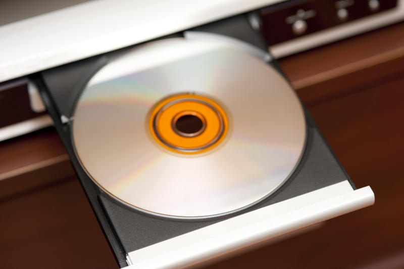 a compact disk laying on the draw of a CD player unit