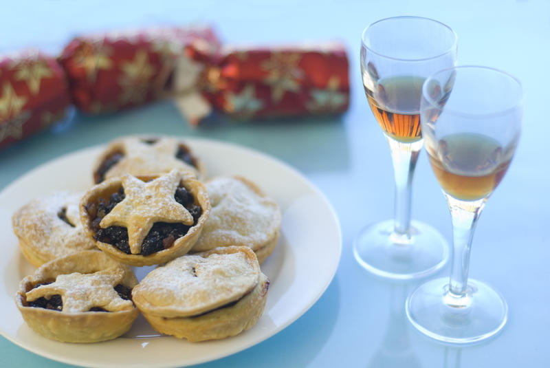 a plate of christmas mince pies, sherry glasses and a pulled cracker