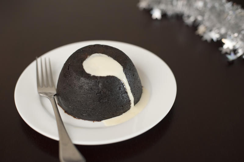 a christmas pudding on a plate with brandy sauce poured over the top