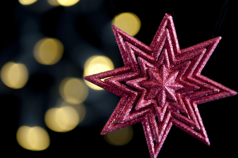 a red christmas star shaped decoration on a background of white defocused christmas lights