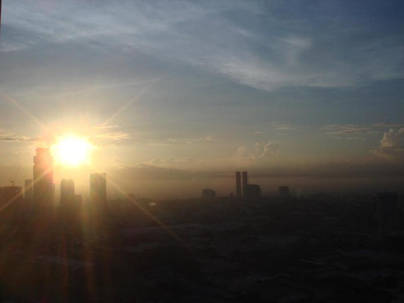 <p>a bright sun hanging low over a urban skyline</p>