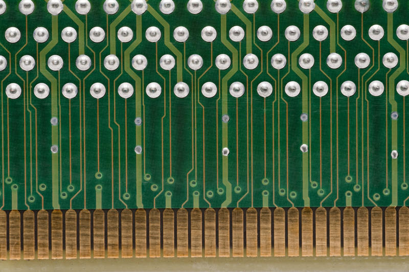 an extreme close up image of tracks near an edge connector on a computer circuit card