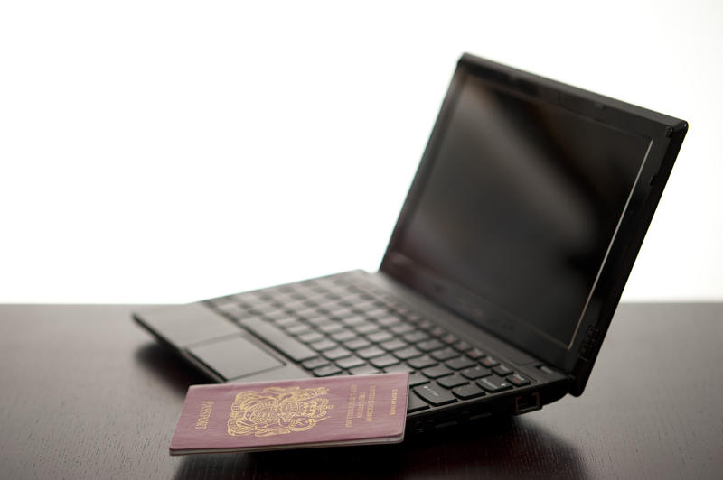 a small laptop computer and passport, concept of cyber border security and overseas internet crime