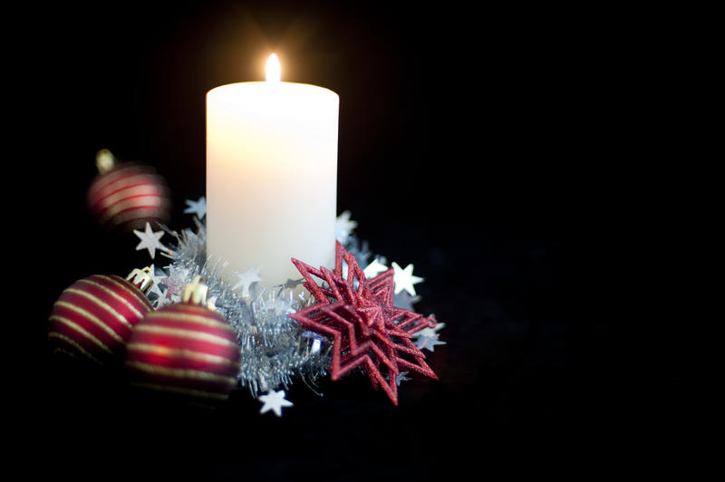 a christmas candle decorated with christmas balls and tinsel
