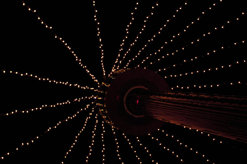 streams of christmas lights hanging from a tower