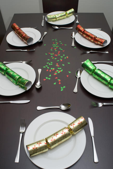 a modern table and chairs set up for dinner with colorful christmas crackers