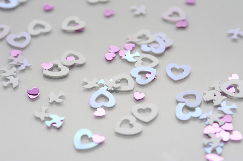 a background of pink and blue colored refective heart shaped confetti