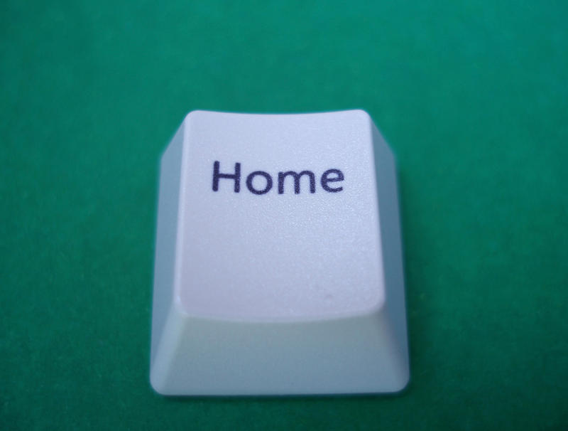 a home button removed form a computer keyboard on a green backdrop