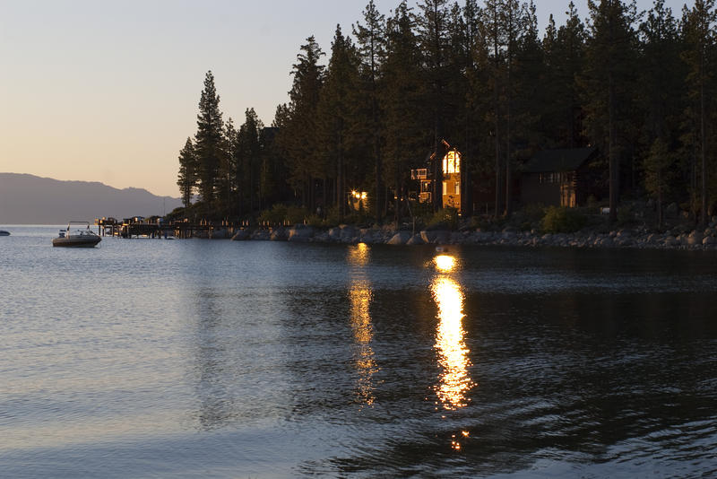 sunset over lake tahoe reflecting off the windows of a lakeside cabin