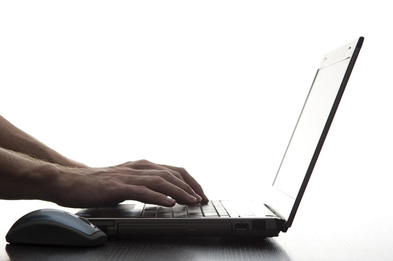 a side view of a computer user with a laptop and wireless mouse