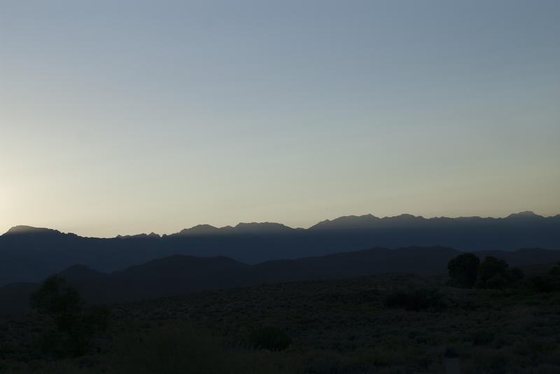 beam of sun lighting up the tops of a mountain range with the last rays of light of the day