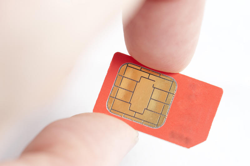 holding a red coloured mobile phone sim card