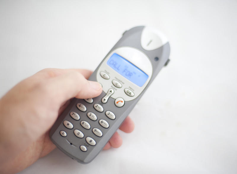 a hand holding a cordless phone taking a call