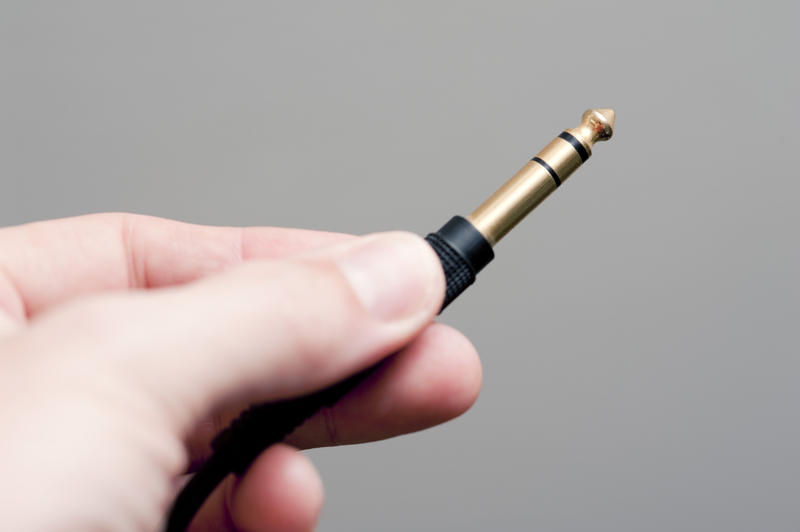 a hand holding a quater inch (6.3mm) stereo jack plug