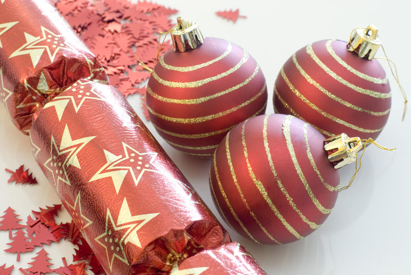 red christmas balls or baubles, cracker and glitter on a white background