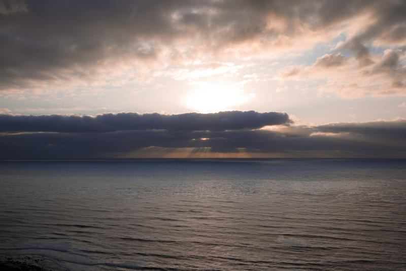 sun beaming out from behind a storm cloud creating a crepuscular light effect