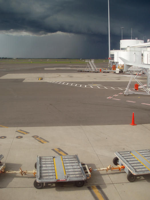 black storm clouds hang over an airport runway