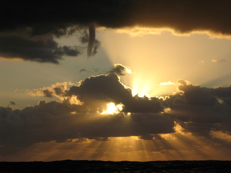 sunbeams shine out from a cloudy sky