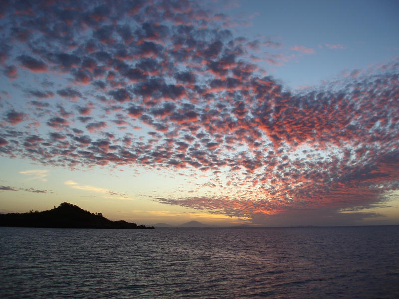 sun setting over a small island and coastal waters