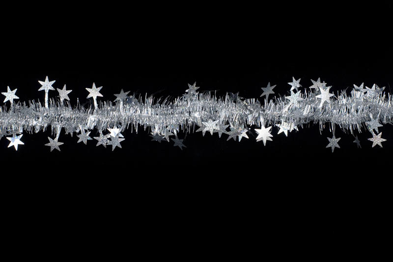 a line of silver tinsel with star shapes on a black background 